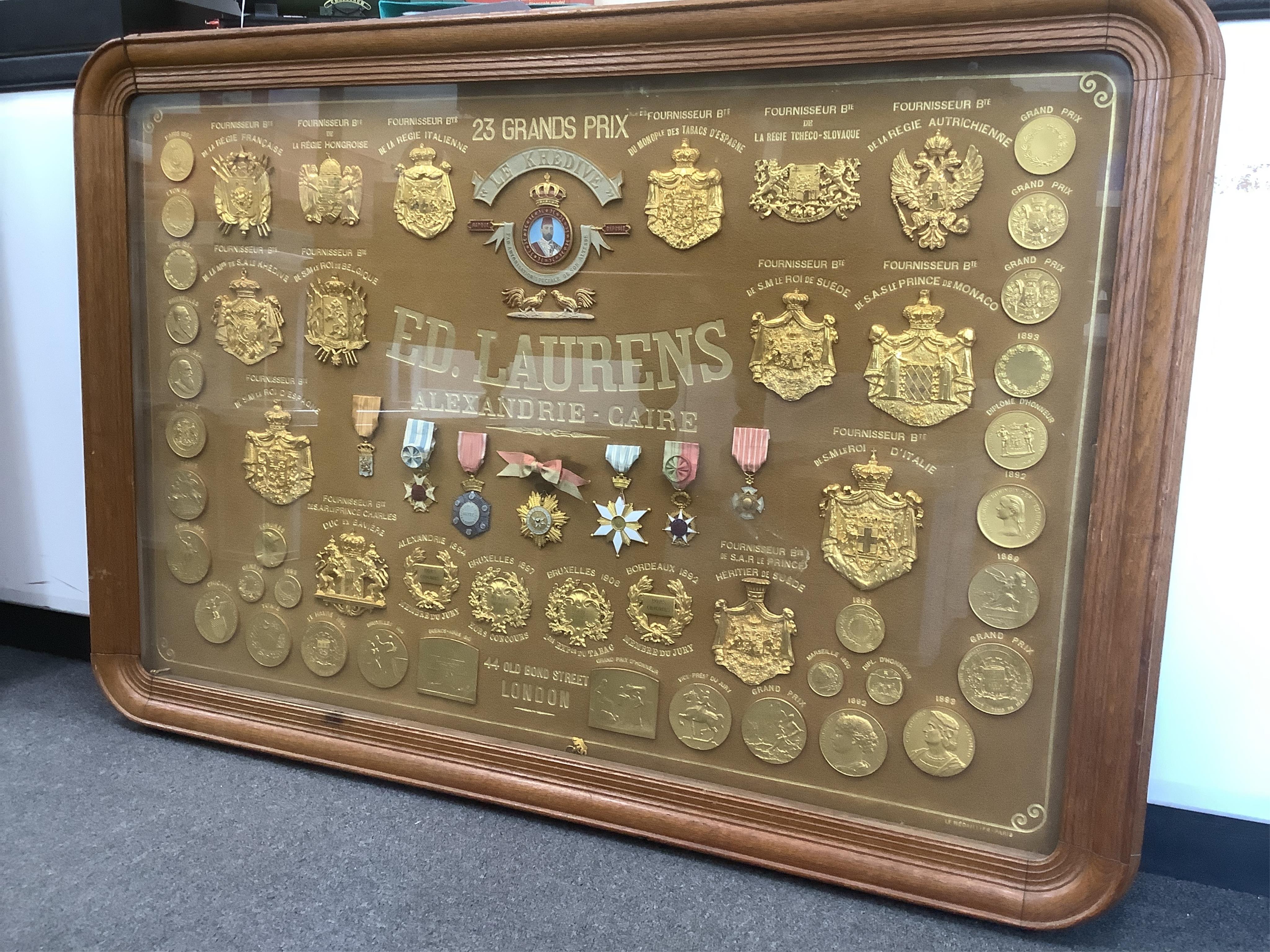 Smoking interest, a large oak framed display of gilt and enamel metal medals to Ed. Laurens, early 20th century, Containing gilt bronze prize medals, ranging from 1890-1906, various gilt and enamel medals with ribbons an